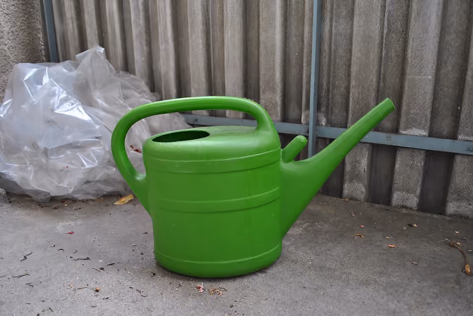 Arrosoir vert en plastique posé au jardin.