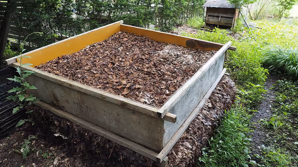 Bac surélevé rempli de feuilles mortes conservées au jardin.