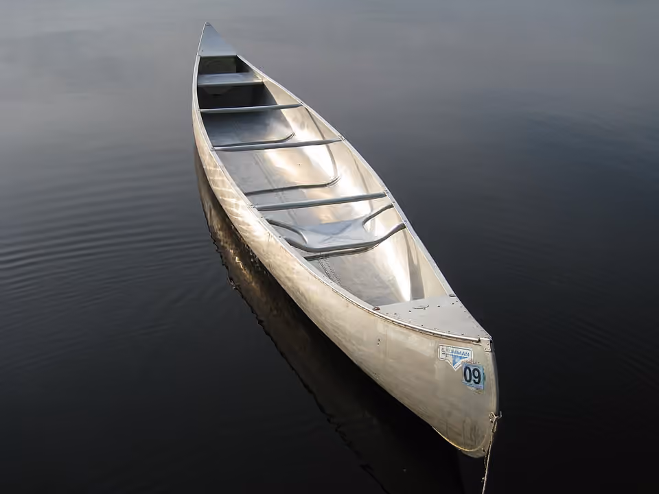 Canoë en aluminium flottant sur une eau calme.