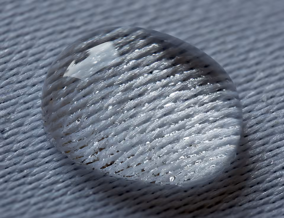Goutte d’eau bombée posée sur un tissu damassé.