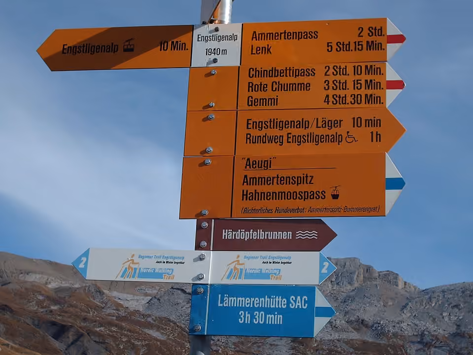 Des panneaux directionnels de randonnée indiquent plusieurs destinations en montagne.