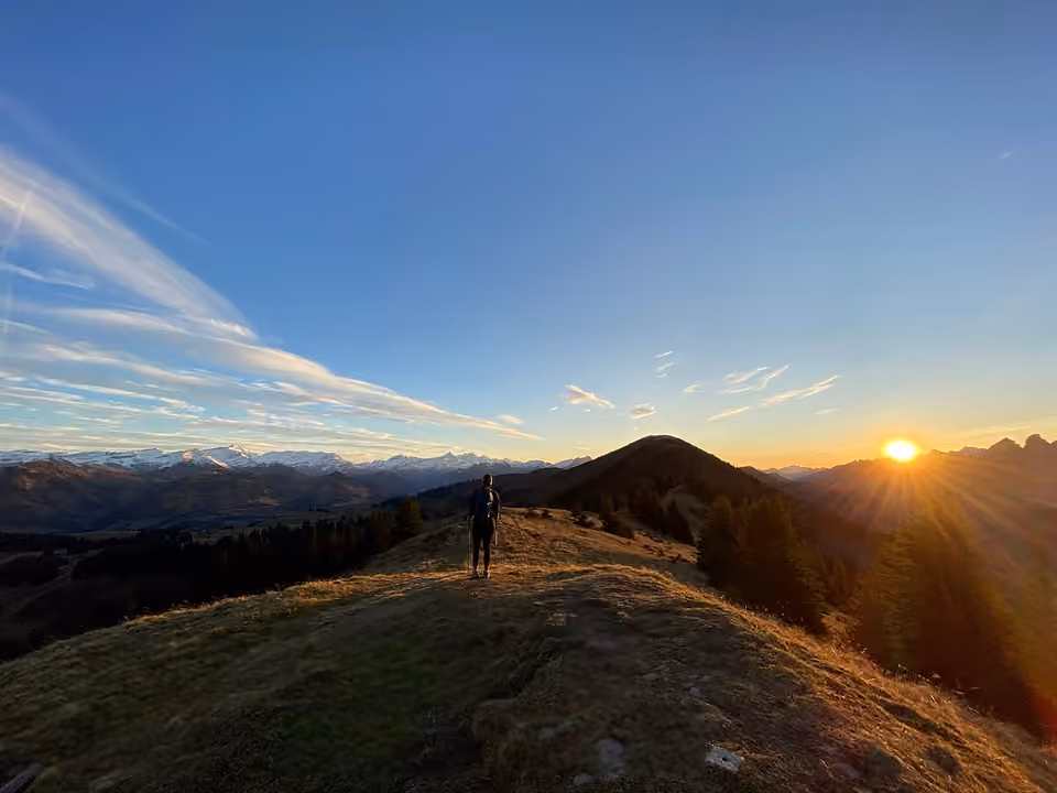 Un randonneur progresse sur une crête alors que le soleil se couche, près du col de Jaun en Suisse.